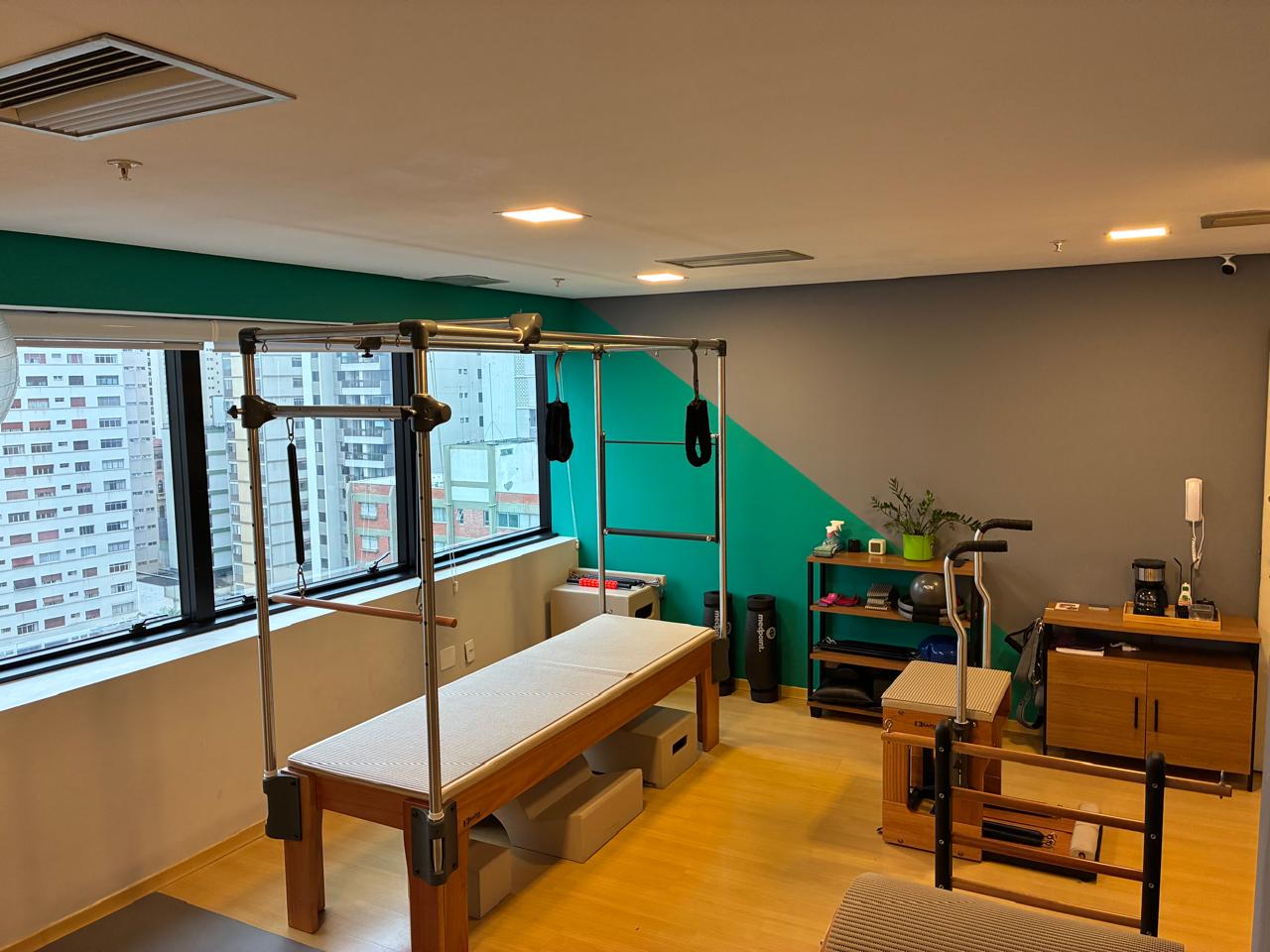 Sala do Voll Pilates Perdizes com trapézio, aparelhos e janelas amplas com vista da cidade